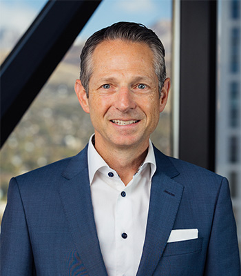 Picture of Derek Miller, President and CEO of Utah Chamber smiling with a suit.